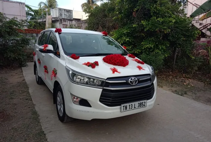 White Innova Crysta decorated with red roses and ribbons for a wedding