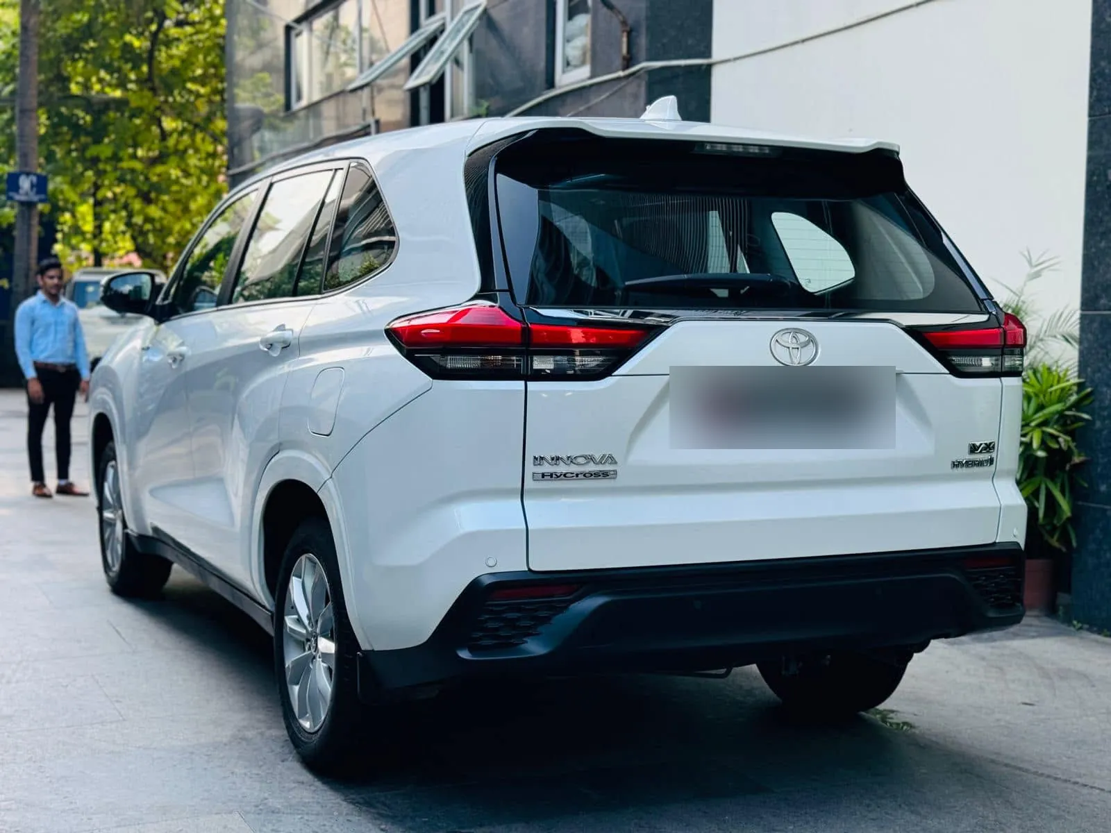 Rear view of a white Innova Hycross hybrid showing the tail lamps and badge