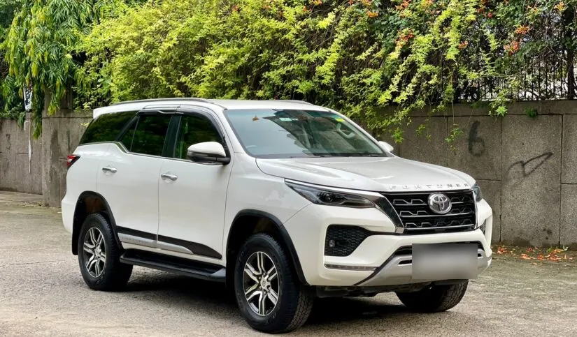 White Toyota Fortuner parked on a tree-lined street, ready for a chauffeur-driven booking