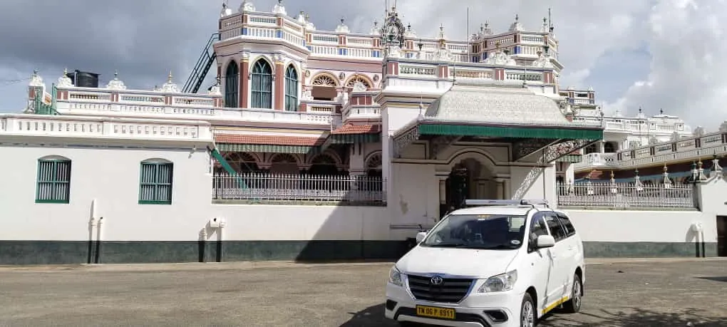 White Toyota Innova taxi parked outside a heritage mansion during a Tamil Nadu tour
